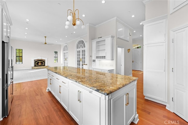 kitchen featuring stainless steel fridge with ice dispenser, white cabinets, ceiling fan with notable chandelier, and a kitchen island