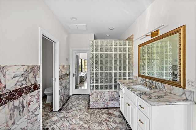 bathroom with vanity, tile walls, and toilet