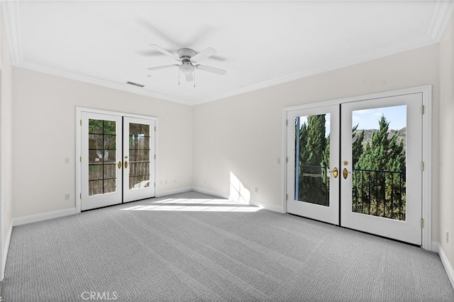 carpeted spare room with ceiling fan, ornamental molding, a wealth of natural light, and french doors