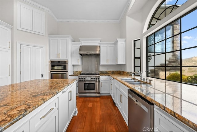 kitchen featuring appliances with stainless steel finishes, white cabinetry, and wall chimney range hood