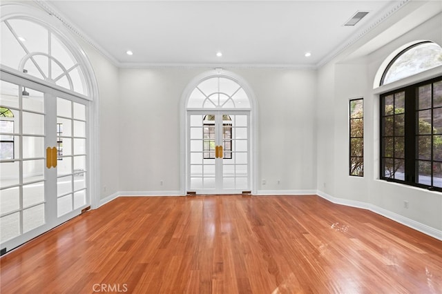 empty room with light wood-type flooring, crown molding, and french doors