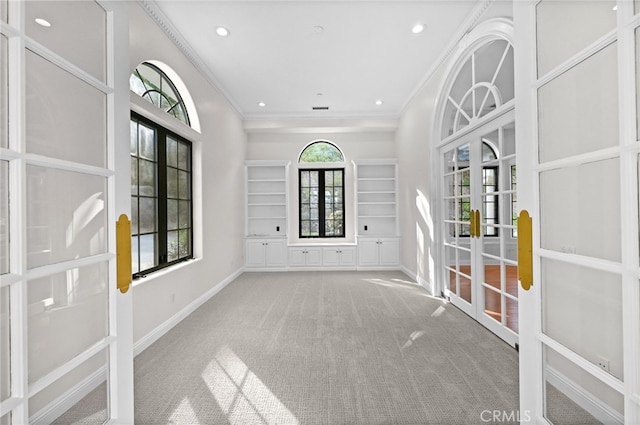 interior space featuring a healthy amount of sunlight, carpet floors, ornamental molding, and french doors