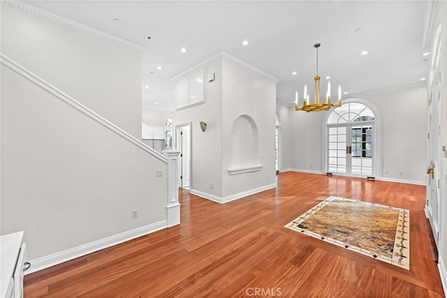 foyer entrance featuring crown molding, light hardwood / wood-style flooring, and a chandelier