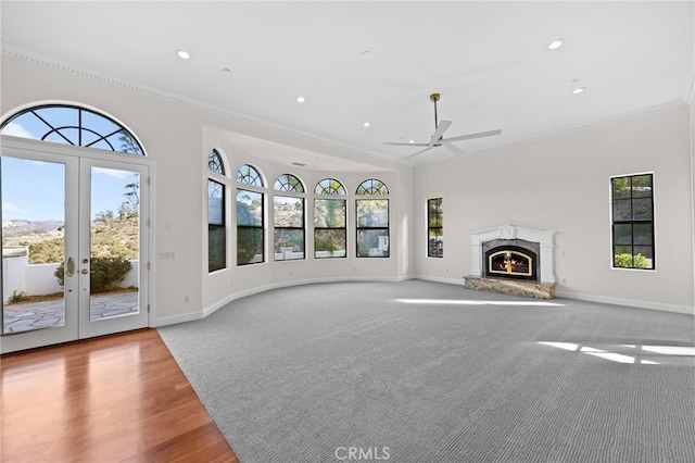 unfurnished living room featuring french doors, light wood-type flooring, ceiling fan, and a healthy amount of sunlight