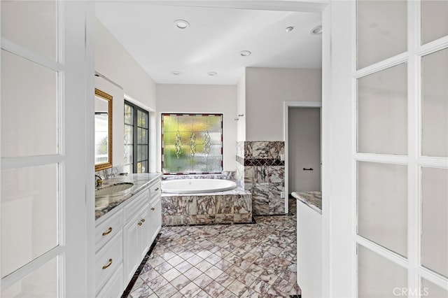 bathroom with vanity and a relaxing tiled tub