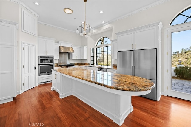 kitchen with a kitchen island, dark hardwood / wood-style flooring, stainless steel appliances, and range hood