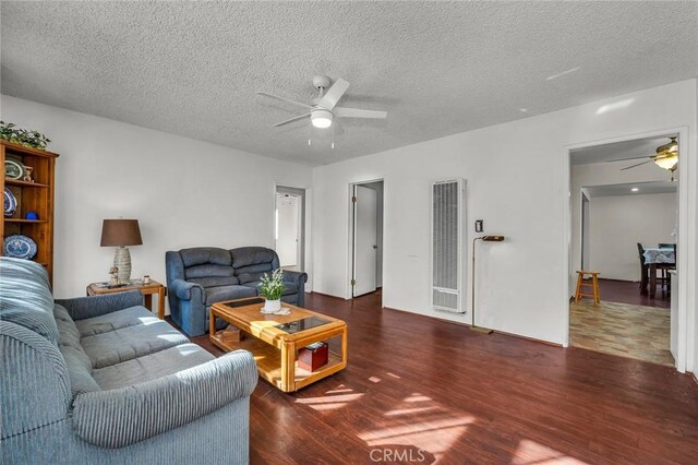 living room featuring a textured ceiling, dark wood-type flooring, and ceiling fan