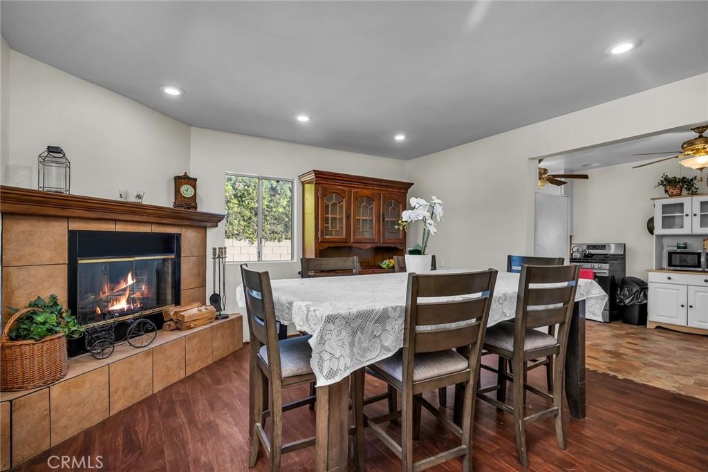 dining area with ceiling fan, dark hardwood / wood-style floors, and a tiled fireplace