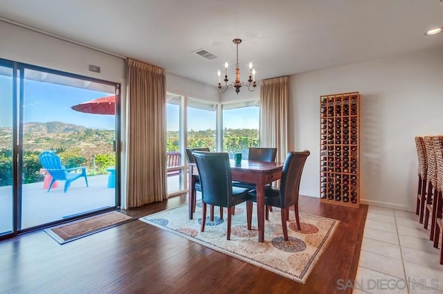 dining area featuring a mountain view, light hardwood / wood-style floors, and an inviting chandelier