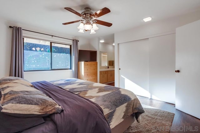 bedroom with ceiling fan, sink, connected bathroom, dark hardwood / wood-style floors, and a closet