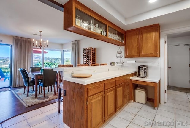 kitchen with a notable chandelier, a healthy amount of sunlight, kitchen peninsula, and hanging light fixtures