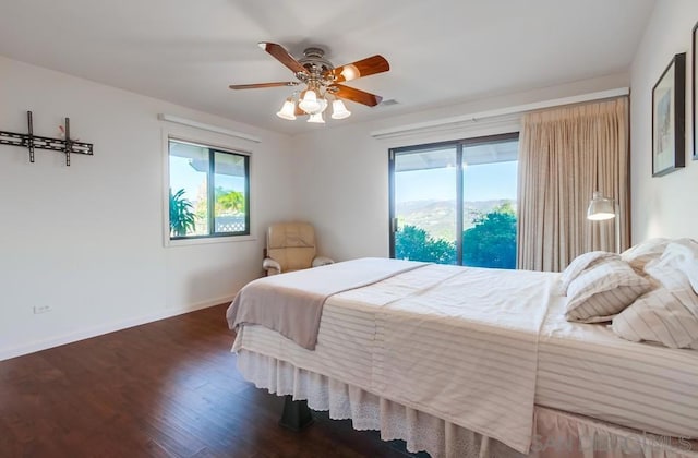 bedroom featuring dark hardwood / wood-style flooring, multiple windows, and ceiling fan