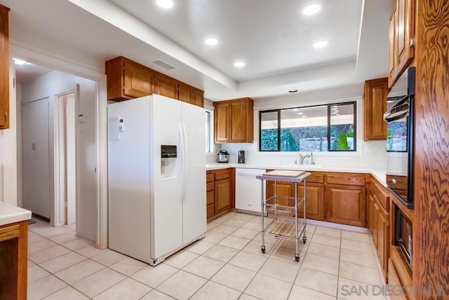 kitchen featuring white appliances, backsplash, a raised ceiling, and light tile patterned flooring