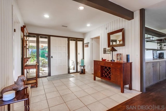 entrance foyer featuring beamed ceiling, wood walls, and light tile patterned floors