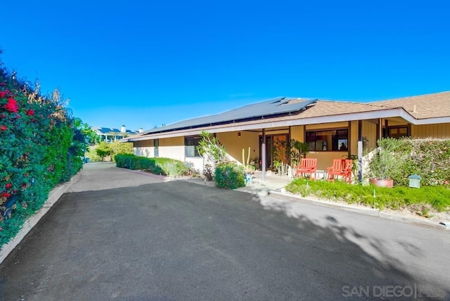 ranch-style house with solar panels and a porch