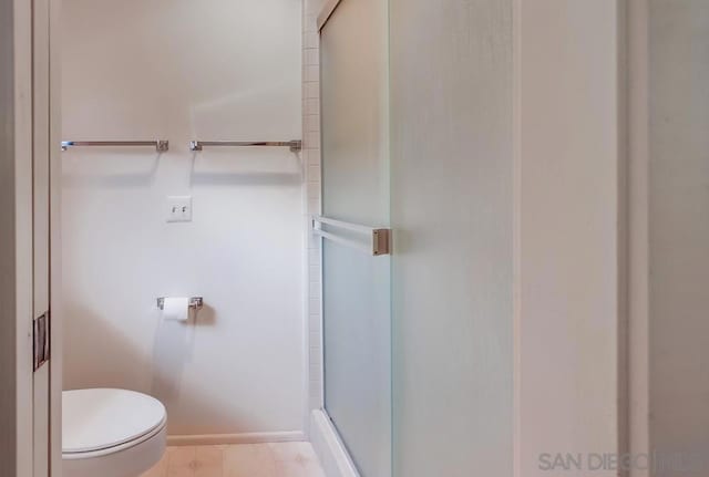 bathroom featuring a shower with shower door and toilet