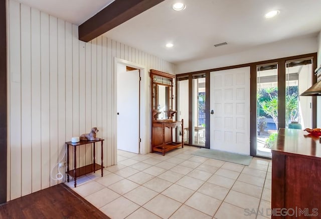 tiled entrance foyer featuring beamed ceiling and wooden walls