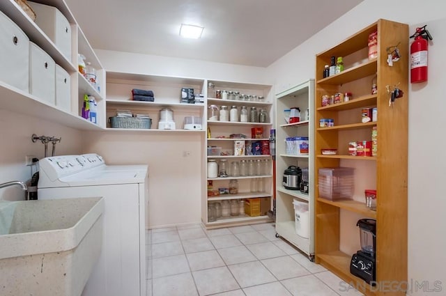 laundry area with light tile patterned floors, sink, and washing machine and clothes dryer