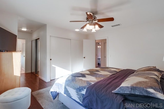 bedroom with ceiling fan, dark hardwood / wood-style flooring, and two closets