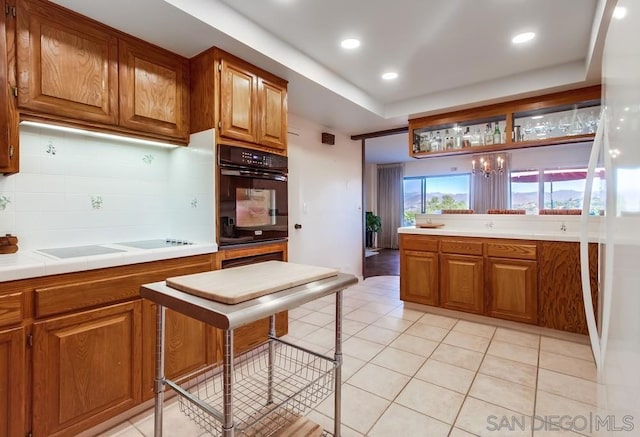 kitchen with cooktop, black oven, decorative backsplash, and light tile patterned floors