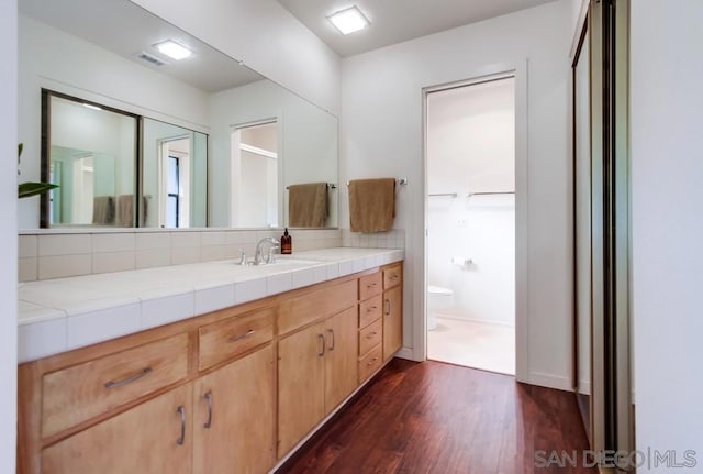 bathroom featuring vanity, toilet, wood-type flooring, and backsplash