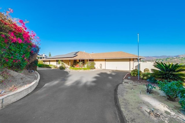 ranch-style house with solar panels, a garage, and a mountain view