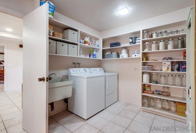 clothes washing area featuring washer and dryer, light tile patterned floors, and sink