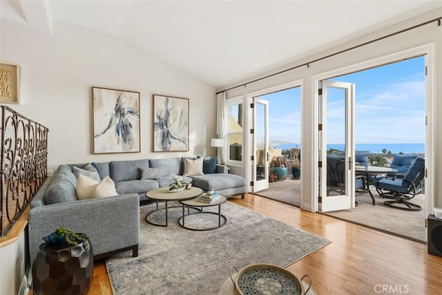 living room featuring a water view, lofted ceiling, french doors, and hardwood / wood-style floors