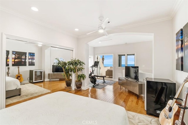 bedroom with ceiling fan, ornamental molding, a closet, and hardwood / wood-style flooring