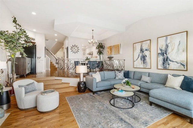 living room featuring light wood-type flooring, vaulted ceiling, and a chandelier