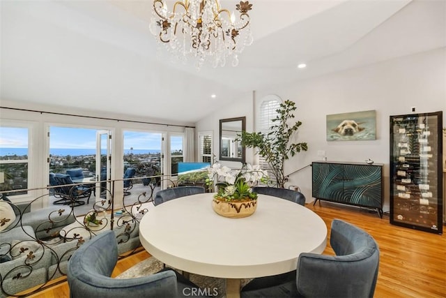 dining space featuring vaulted ceiling, wine cooler, light wood-type flooring, and a notable chandelier