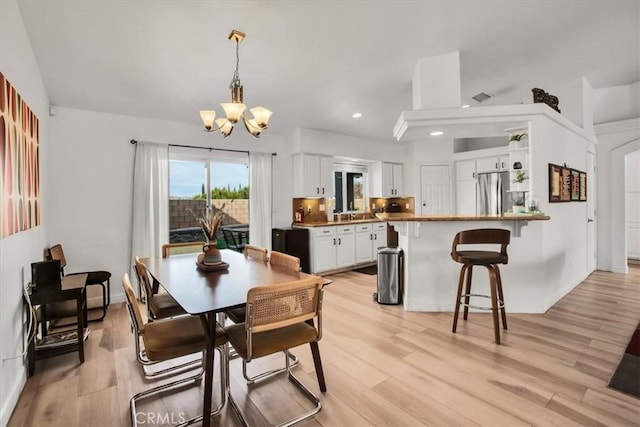 dining space with a notable chandelier and light hardwood / wood-style floors