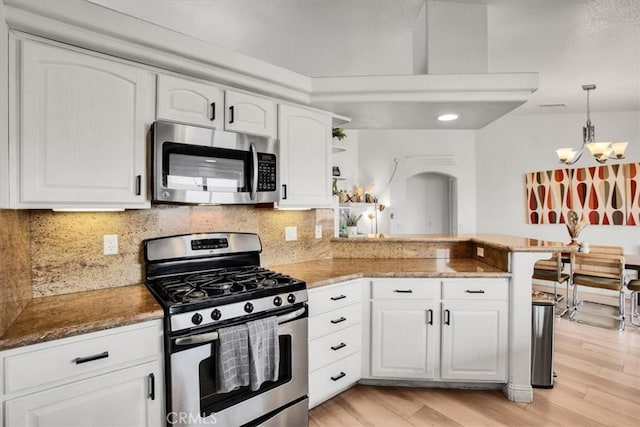 kitchen featuring kitchen peninsula, light hardwood / wood-style floors, decorative light fixtures, white cabinets, and appliances with stainless steel finishes