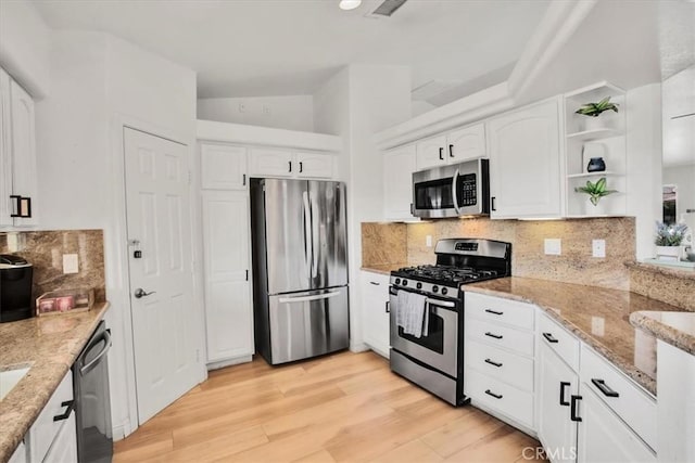 kitchen featuring light stone countertops, white cabinetry, light hardwood / wood-style floors, and appliances with stainless steel finishes