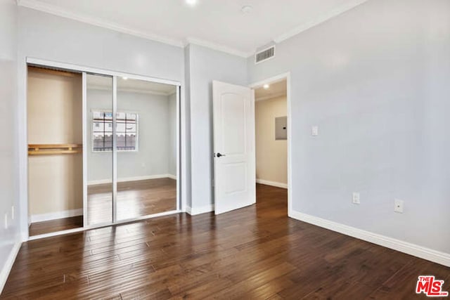 unfurnished bedroom featuring crown molding, dark wood-type flooring, and a closet