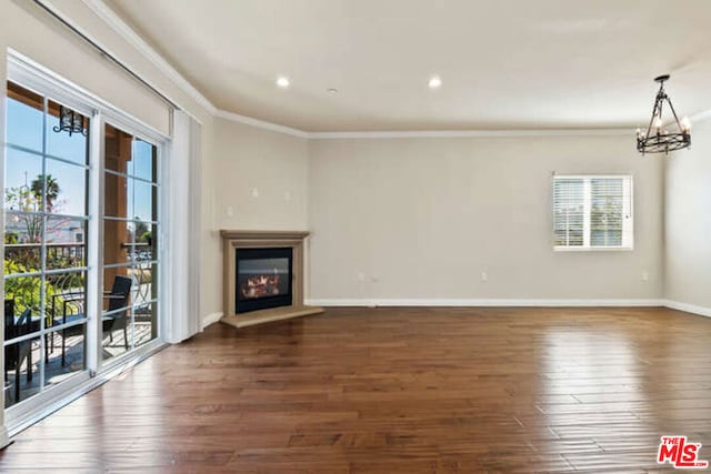 unfurnished living room featuring an inviting chandelier, ornamental molding, and dark hardwood / wood-style floors