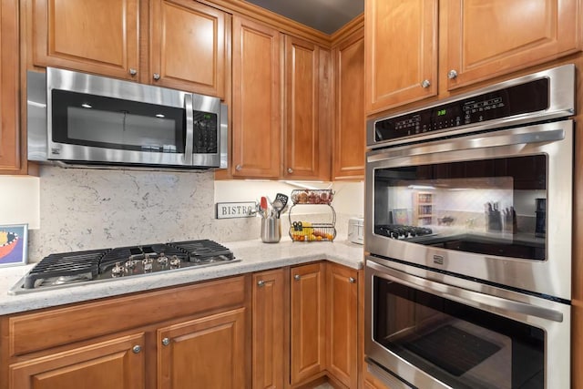 kitchen with light stone countertops, appliances with stainless steel finishes, and tasteful backsplash