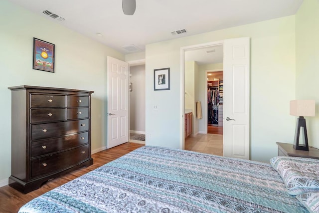 bedroom featuring hardwood / wood-style floors, a walk in closet, a closet, and ceiling fan