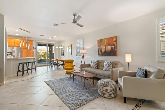 living room featuring light tile patterned floors and ceiling fan with notable chandelier