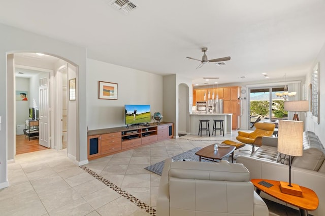 tiled living room featuring ceiling fan with notable chandelier