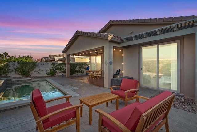 patio terrace at dusk featuring ceiling fan and a fenced in pool