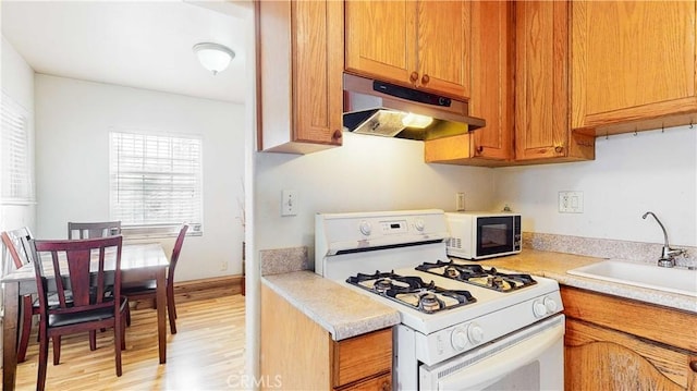 kitchen with sink, white appliances, and light wood-type flooring