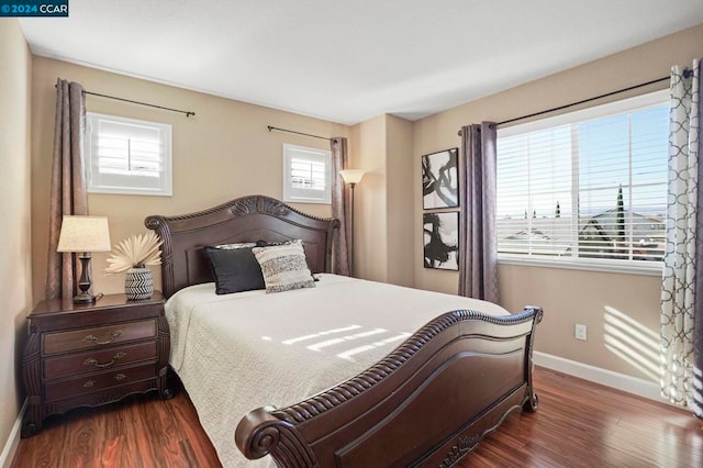 bedroom with dark hardwood / wood-style floors and multiple windows