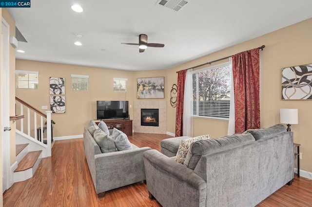 living room with ceiling fan, a fireplace, and light hardwood / wood-style flooring