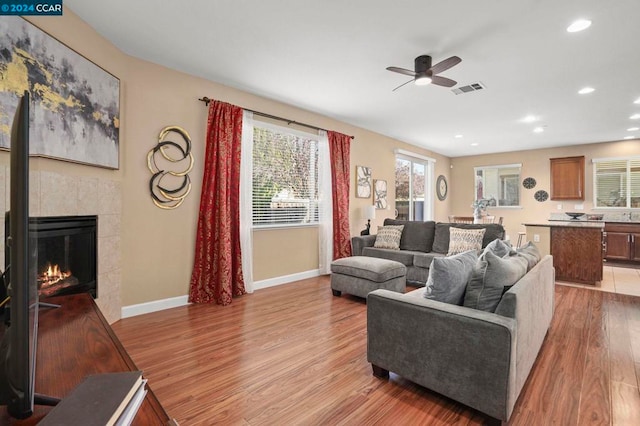 living room featuring ceiling fan, a fireplace, and light hardwood / wood-style flooring