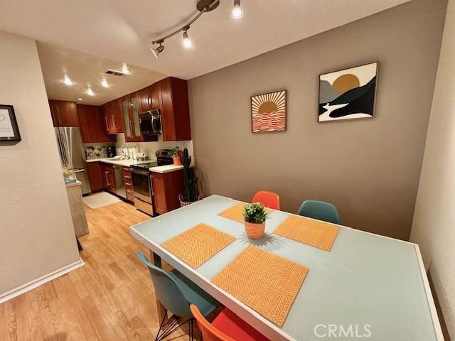 dining room featuring visible vents, baseboards, light wood-style floors, and track lighting