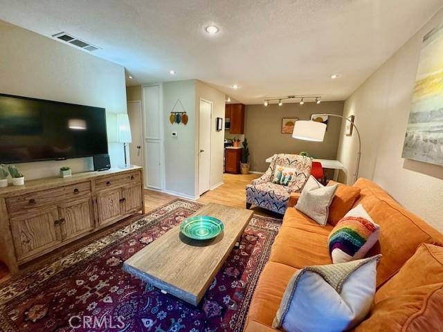 living room with light wood-type flooring, visible vents, recessed lighting, rail lighting, and baseboards