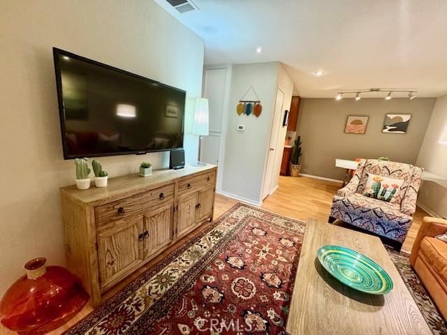 living area with visible vents, rail lighting, baseboards, and light wood-style floors