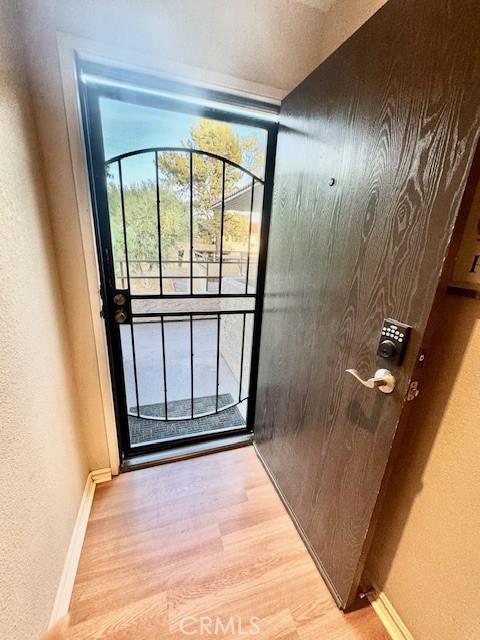 2810 N Arcadia Ct Unit 208, Palm Springs, CA 92262 - doorway to outside featuring baseboards, light wood-style floors, and a textured wall