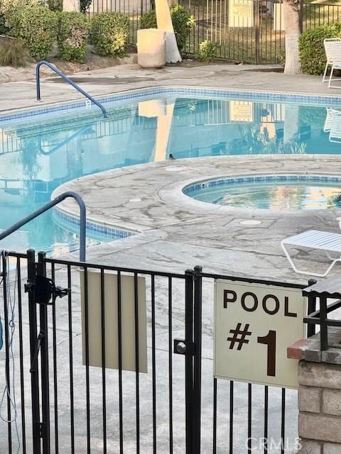 pool featuring an in ground hot tub and fence